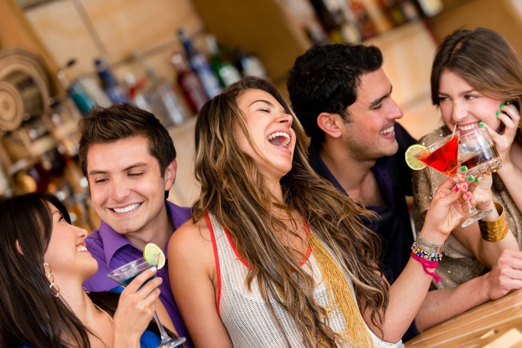 Happy group of friends at the bar having drinks